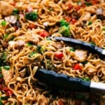 Fnished Chicken Ramen in a skillet with tongs holding some of the noodles.