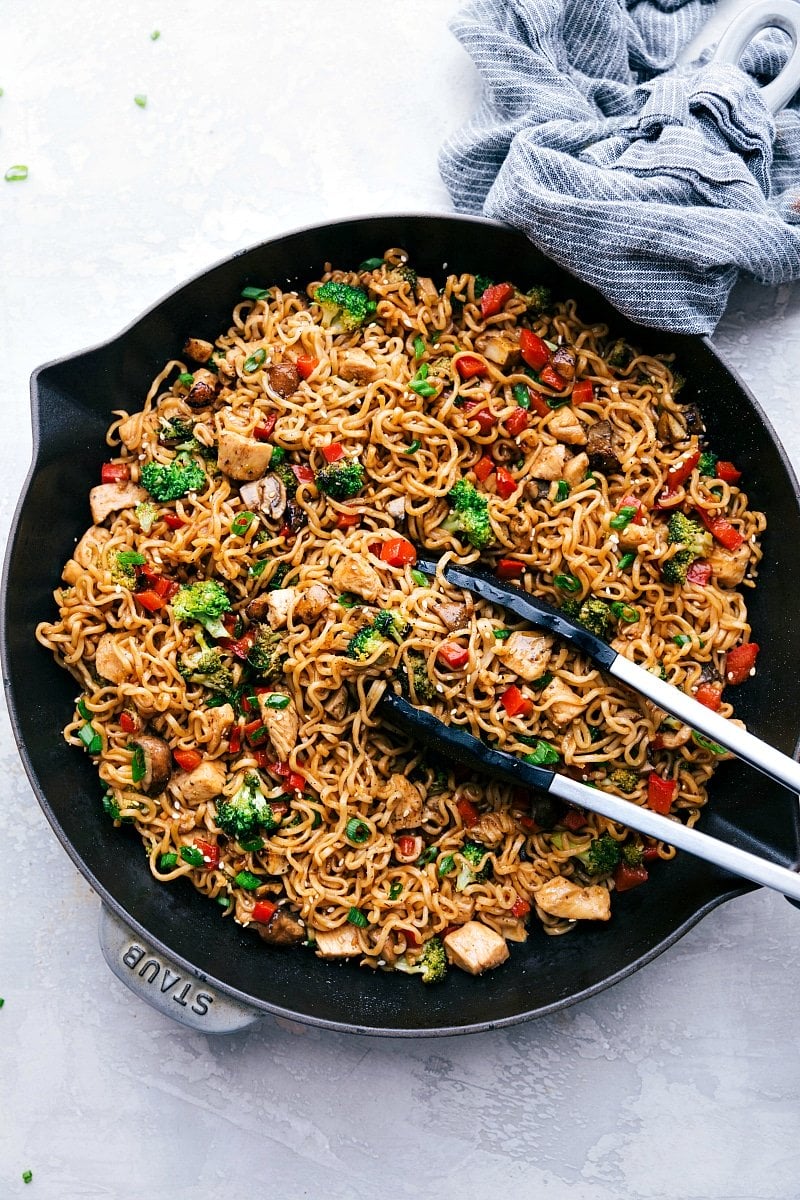 Chicken Ramen in a skillet with tongs holding some of the noodles.