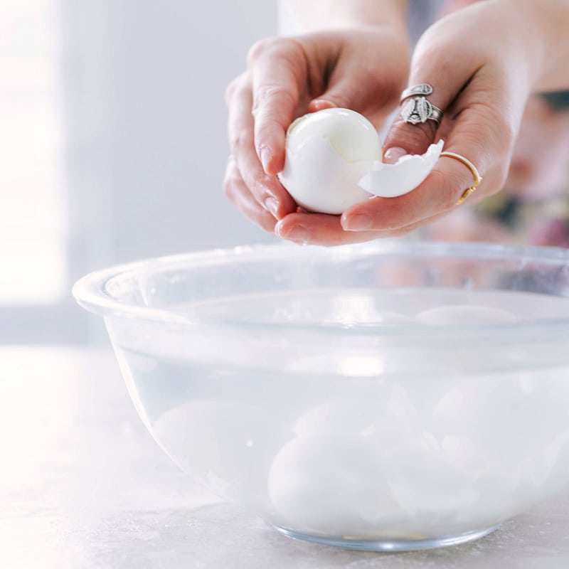 Image of the shell being removed on one of the cooked eggs for this Deviled Eggs recipe.