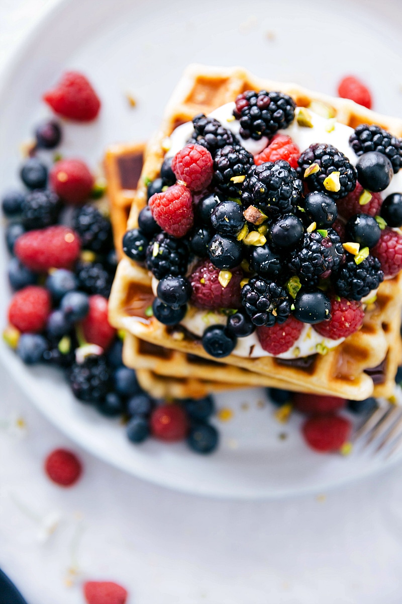 Cooked waffles stacked with berries on top.