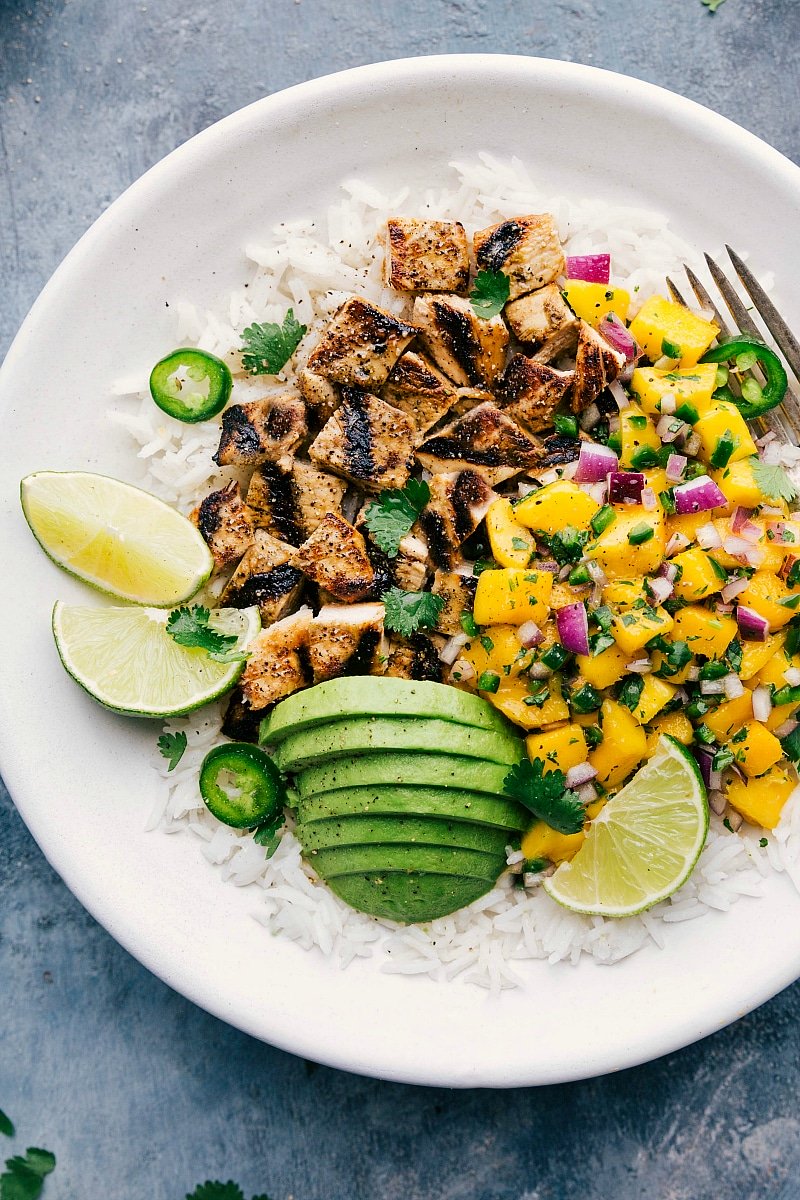 Up-close finished Mango Chicken bowls with avocado and lime wedges.