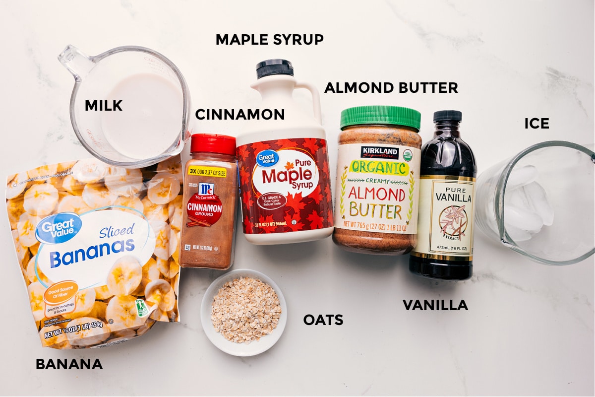 All the ingredients in this recipe prepped out for easy assembly including the bananas, milk, oats, cinnamon, maple syrup, almond butter, vanilla, and ice.