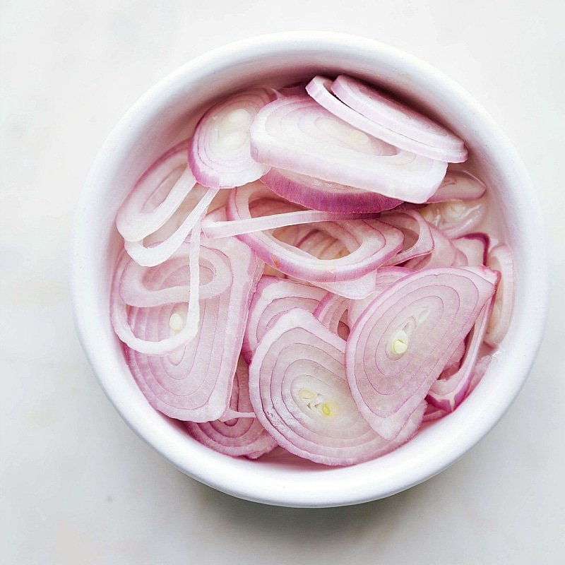 Fresh shallots finely sliced, ready to be used as a topping for the dish.