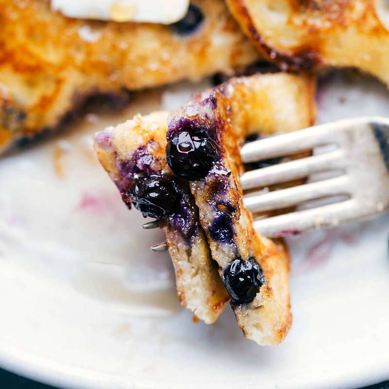 Up close image of a bite of blueberry pancake on a fork