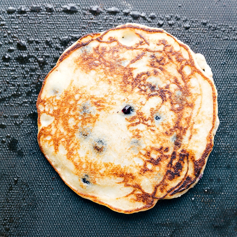 Best blueberry pancake recipe on the griddle after being flipped.