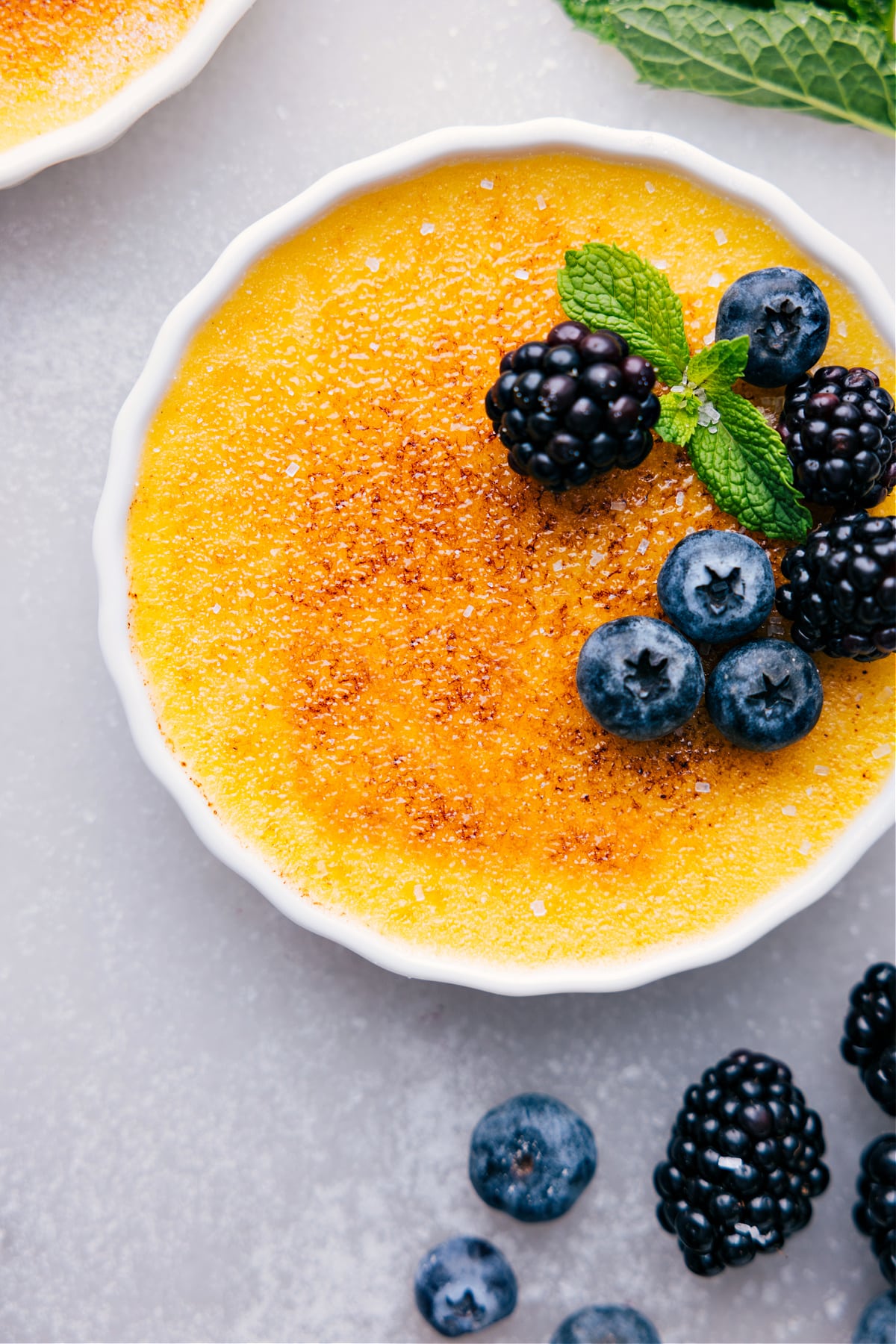 Delicious easy creme brûlée with a caramelized top, garnished with fresh fruit.
