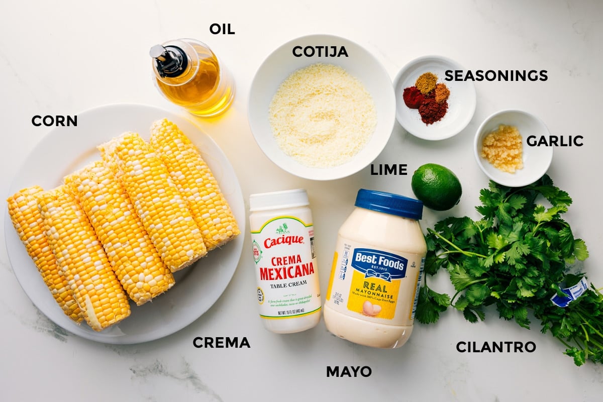Ingredients In This Elote Recipe All the ingredients in this recipe prepped out for easy assembly including the corn, oil, cotija, crema, mayo, cilantro, garlic, lime, and seasonings.