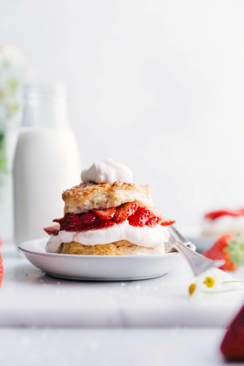 Ready-to-eat Strawberry Shortcake with whipped cream on top and a fork on the side of the plate.