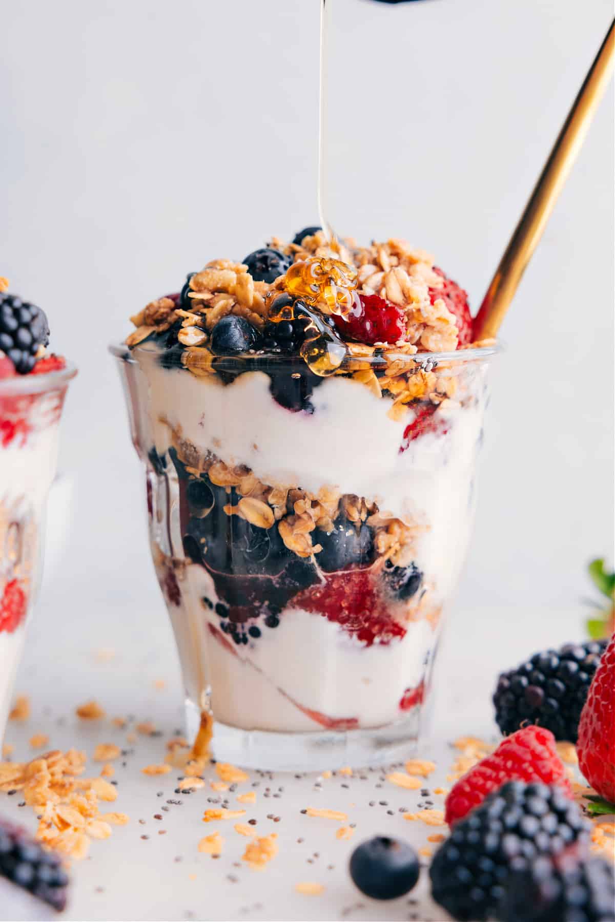 Yogurt parfait with a drizzle of honey being drizzled over it.