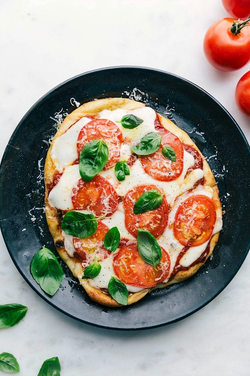 Naan Pizza on a plate, baked with basil on top.