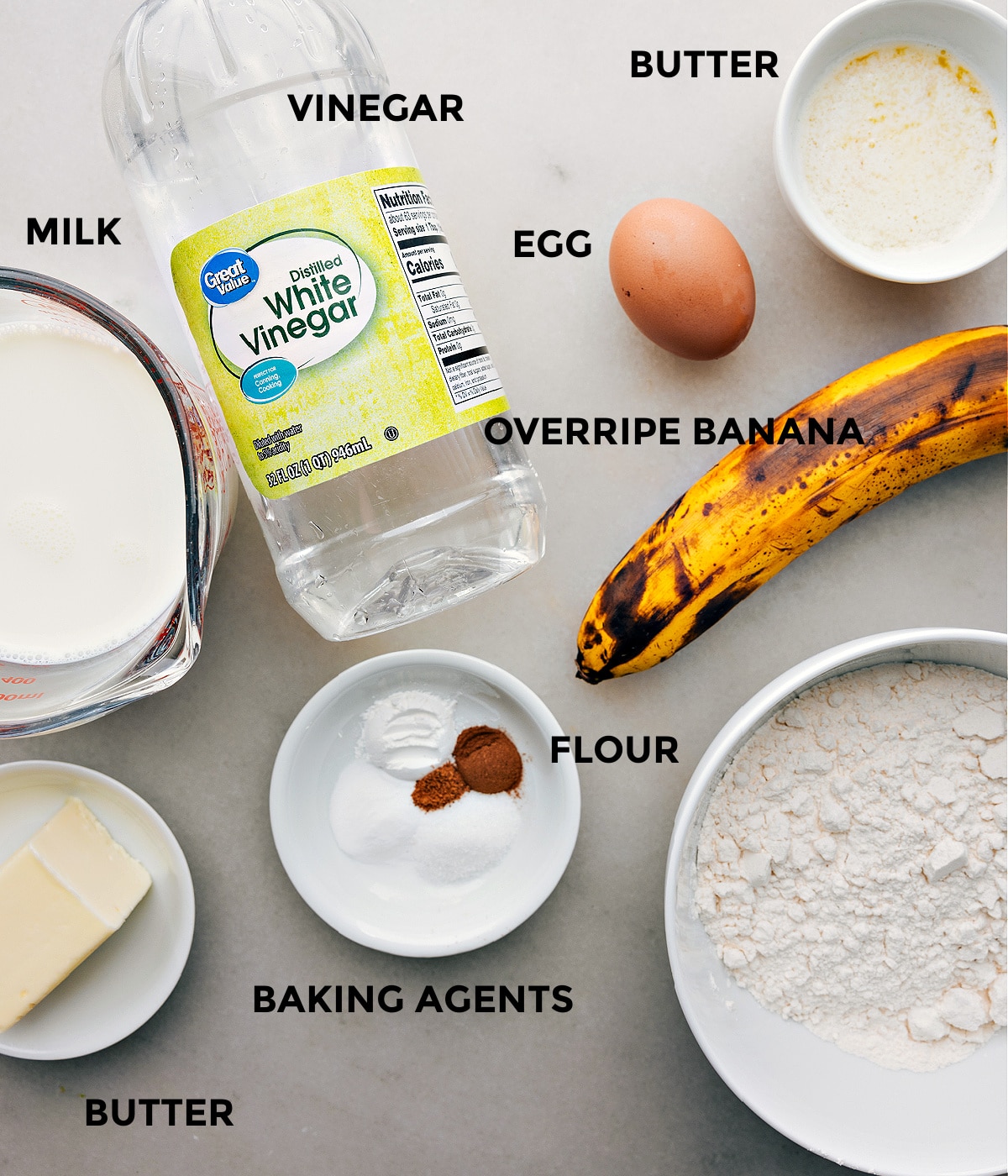 All ingredients for the banana pancake recipe prepped and laid out for easy assembly, including bananas, flour, eggs, and syrup.