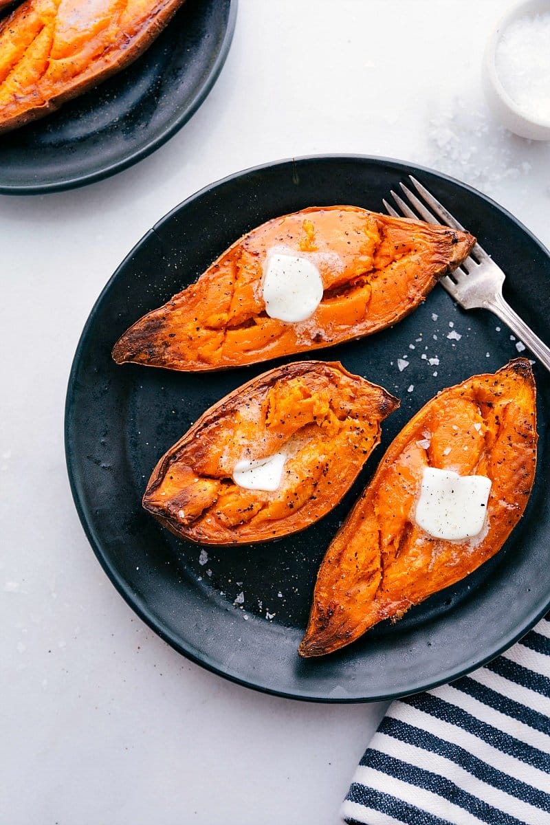 Baked sweet potatoes on a plate with melting butter on top, ready to be enjoyed.