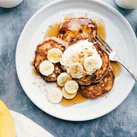 Ready-to-eat Banana Pancakes with syrup and fresh bananas on top.