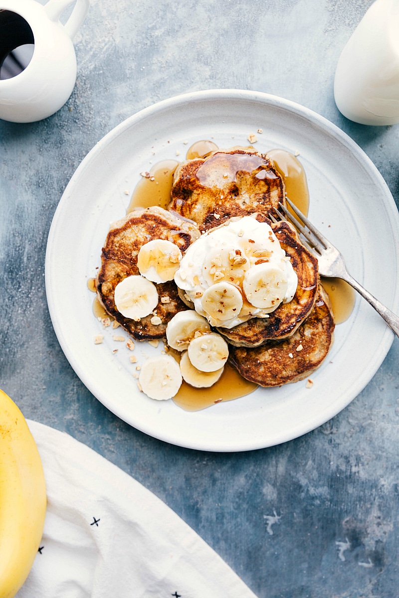 Ready-to-eat Banana Pancakes with syrup and fresh bananas on top.