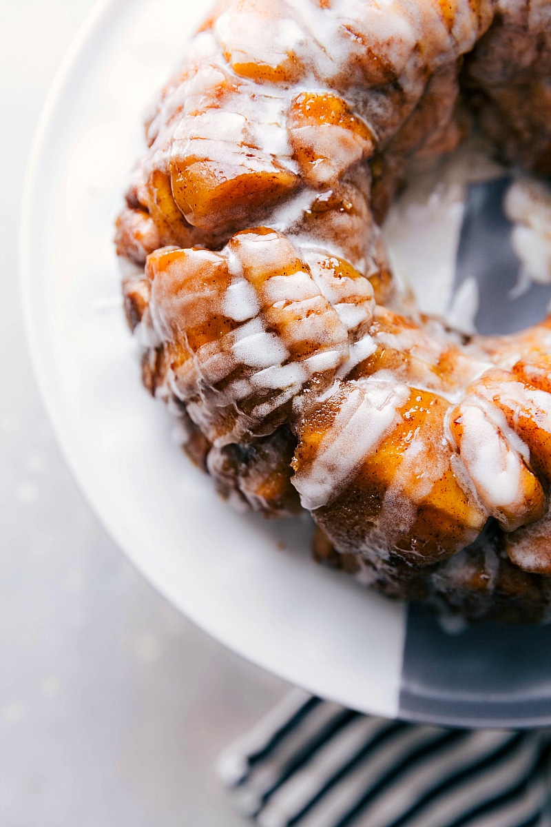 Overhead image of the monkey bread on a cake stand with the frosting glaze over it.