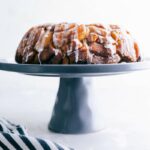 Cinnamon roll monkey bread baked and ready to eat, sitting on a cake stand, with icing dripping, delicious and full of flavor.