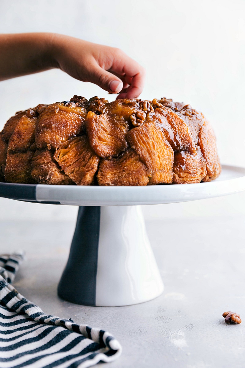 Image of freshly baked Monkey Bread, with a hand reaching to take a piece.