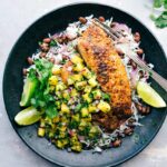 A plate featuring blackened tilapia served with pineapple salsa, rice, and black beans, presenting a flavor-packed and delicious meal.