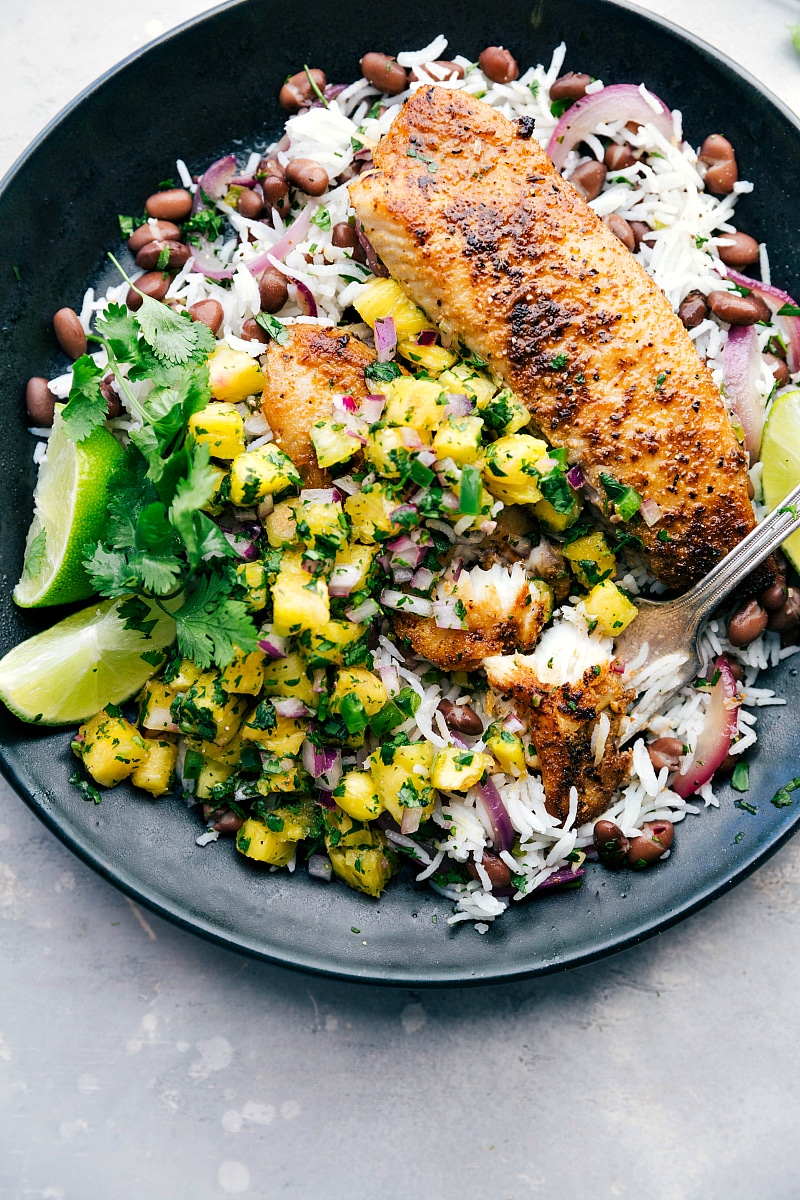 Image of Blackened Tilapia, pineapple salsa, and rice base with a bite out of it.