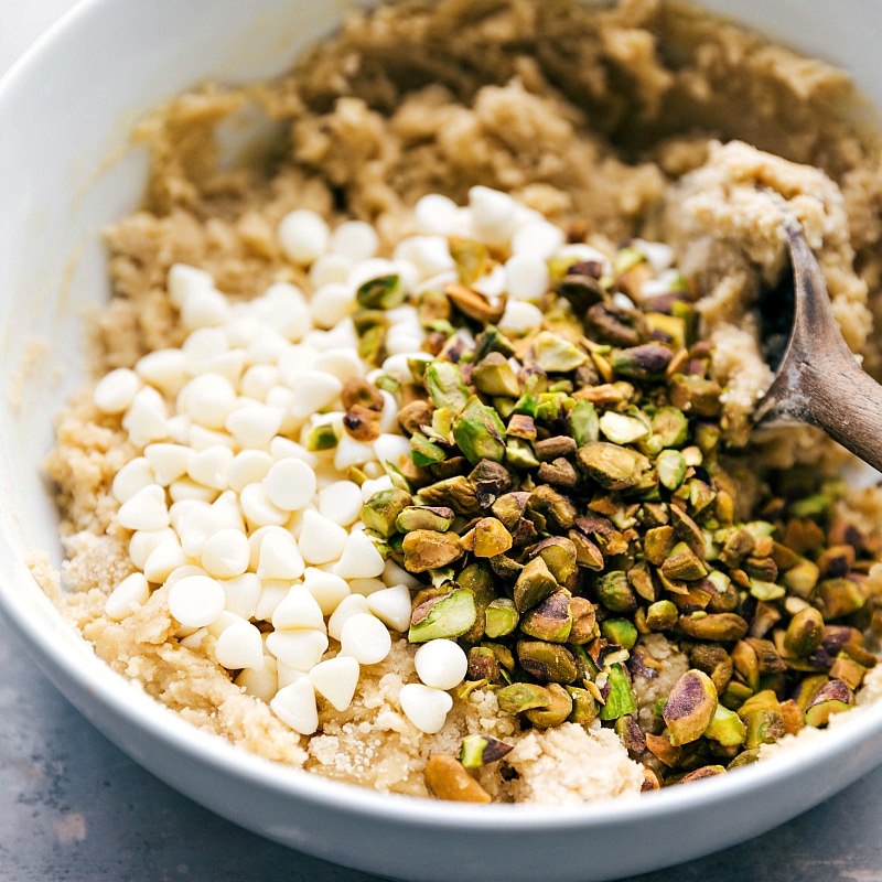 Image of the white chocolate chips and pistachios being added to the dough.