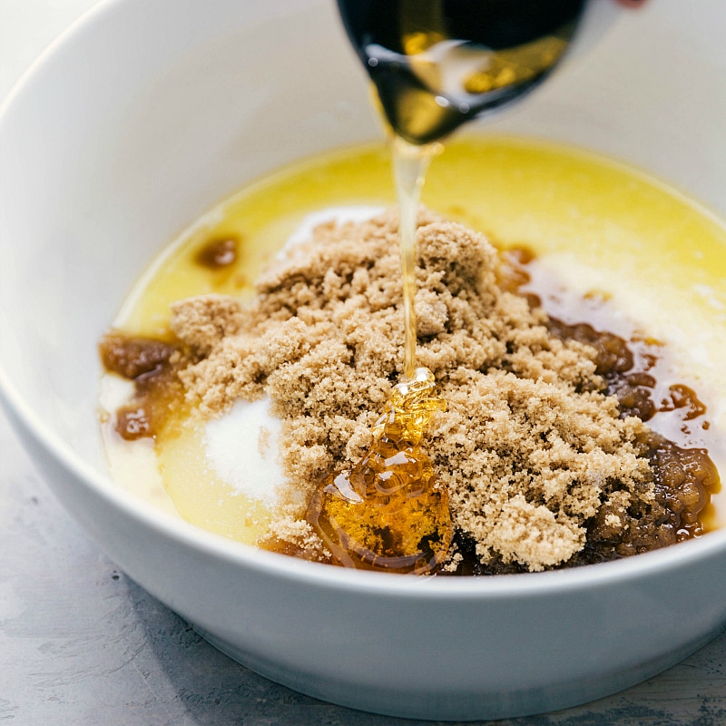 Adding honey to the bowl of wet ingredients, capturing the moment as it pours in, contributing its sweetness to the recipe.