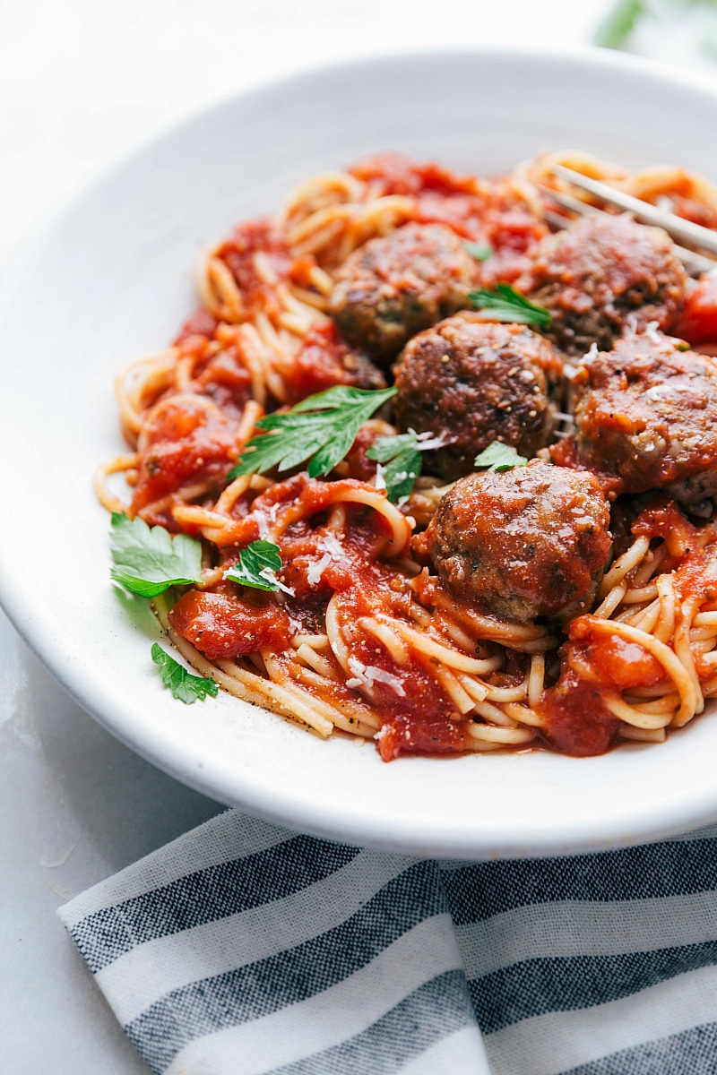 Finished side shot of the best Turkey Meatballs ever, in a bowl with pasta and red sauce on the side