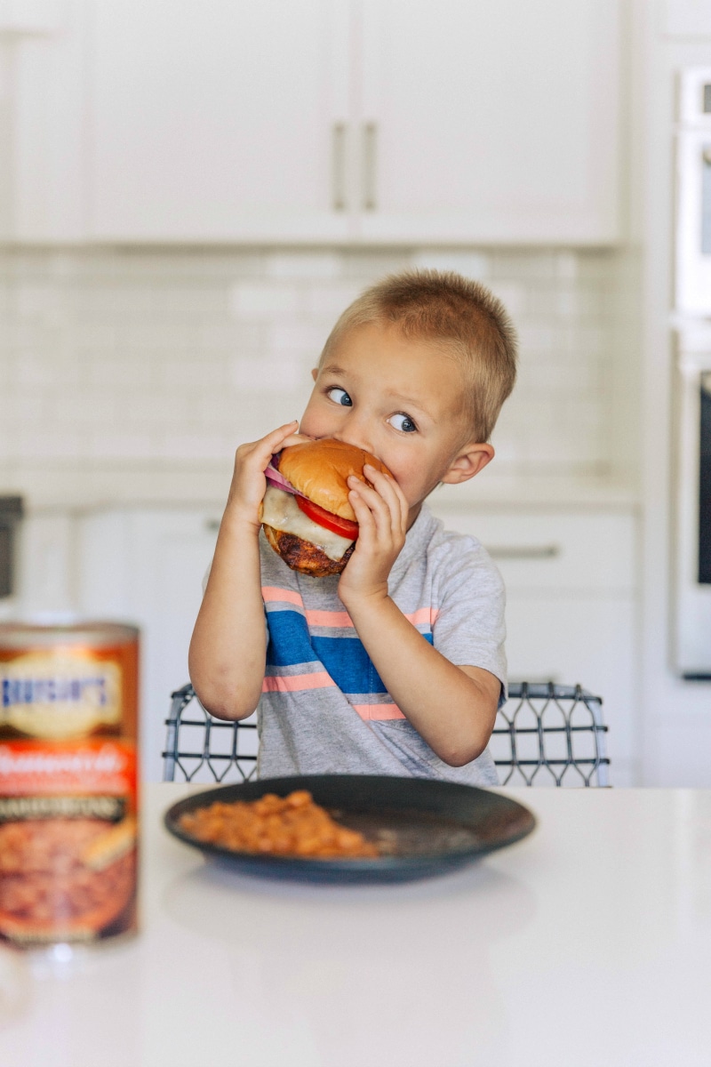 Image of a little boy eating the finished Chicken Burger.