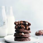 A stack of chocolate cookies with one cookie split in half, revealing its gooey and rich center.