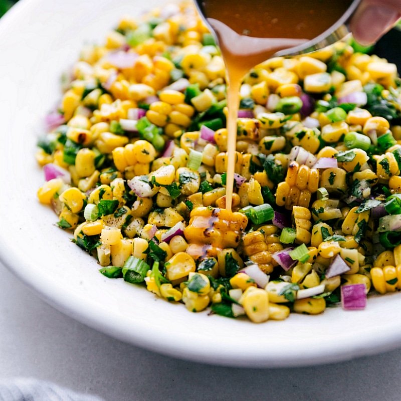 Delicious homemade dressing being poured over the corn salsa recipe, enhancing the flavor.