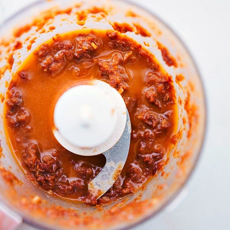 Blending the sun-dried tomato sauce in a food processor, capturing the ingredients coming together to create a flavorful sauce.