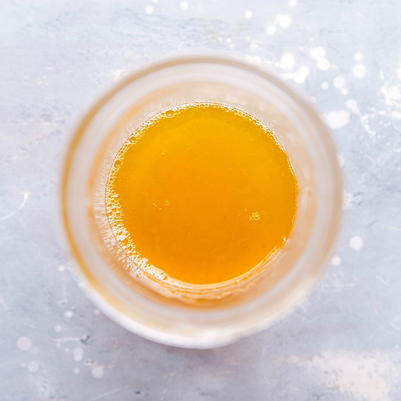 A mason jar filled with freshly strained orange dressing, ready for use, showcasing its bright and inviting color.