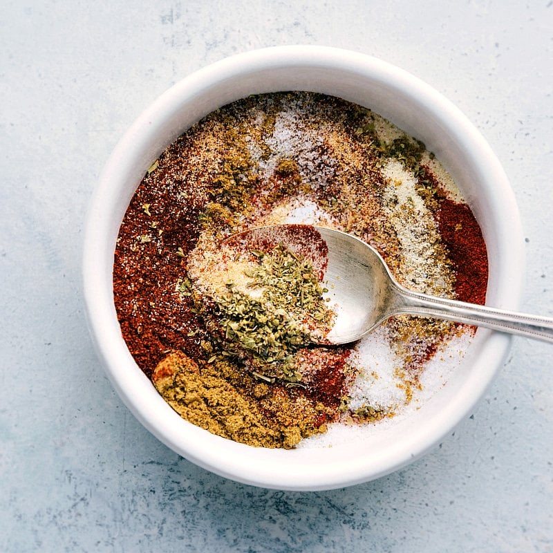 A bowl filled with a mixture of seasonings and spices, being combined to create a flavorful seasoning blend for the shrimp fajita recipe.