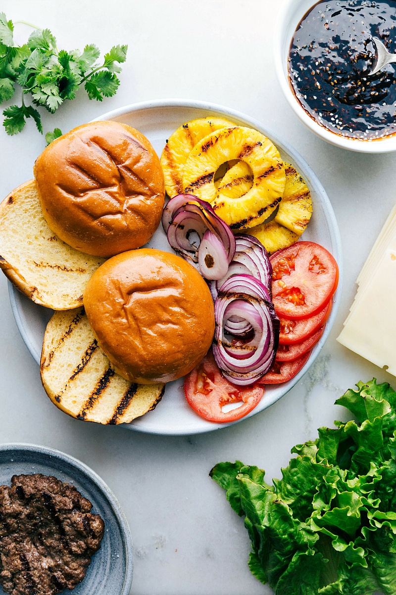 Image of the brioche buns and other toppings, along with the sauce and meat that go on this Teriyaki Burger.