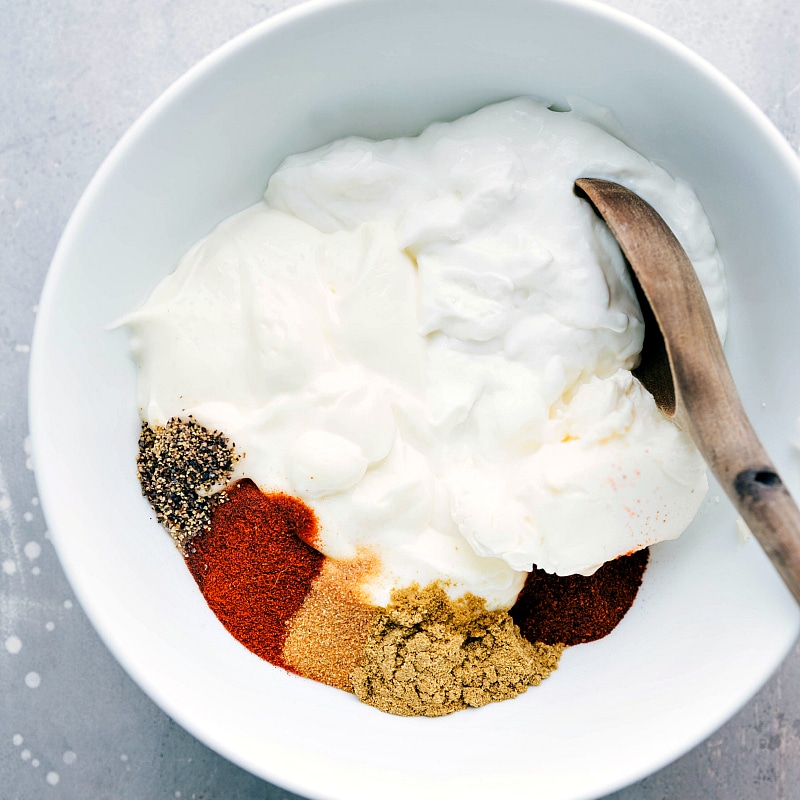 Seasonings and sour cream added to a bowl, ready to be mixed together.