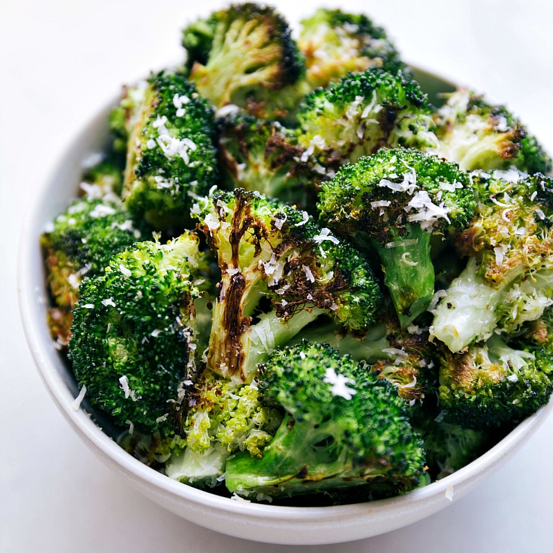 Delicious oven roasted broccoli in a bowl, topped with parmesan cheese, ready to be eaten.