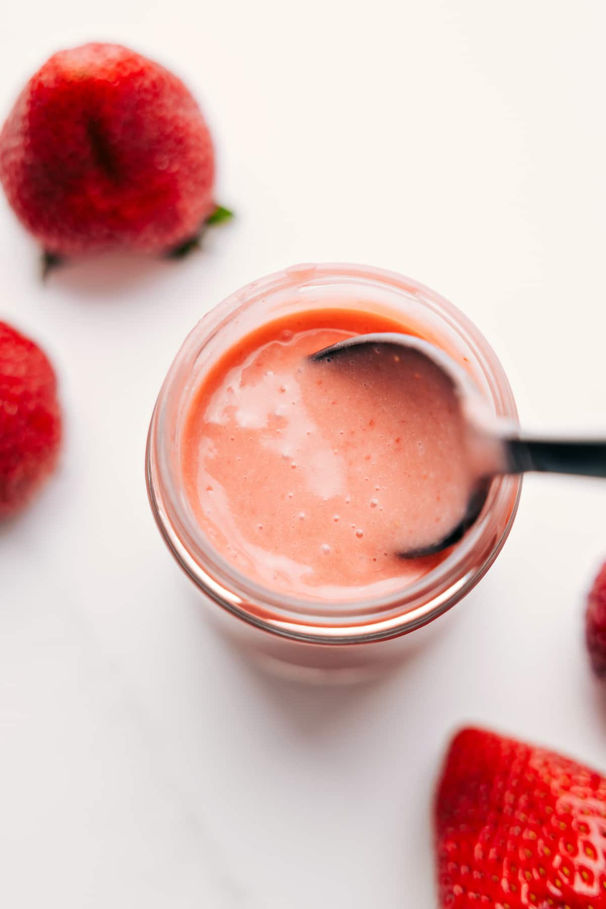 Simple And Delicious Strawberry Vinaigrette Strawberry Vinaigrette in a mason jar with a spoon scooping it up, ready to drizzle and enjoy.