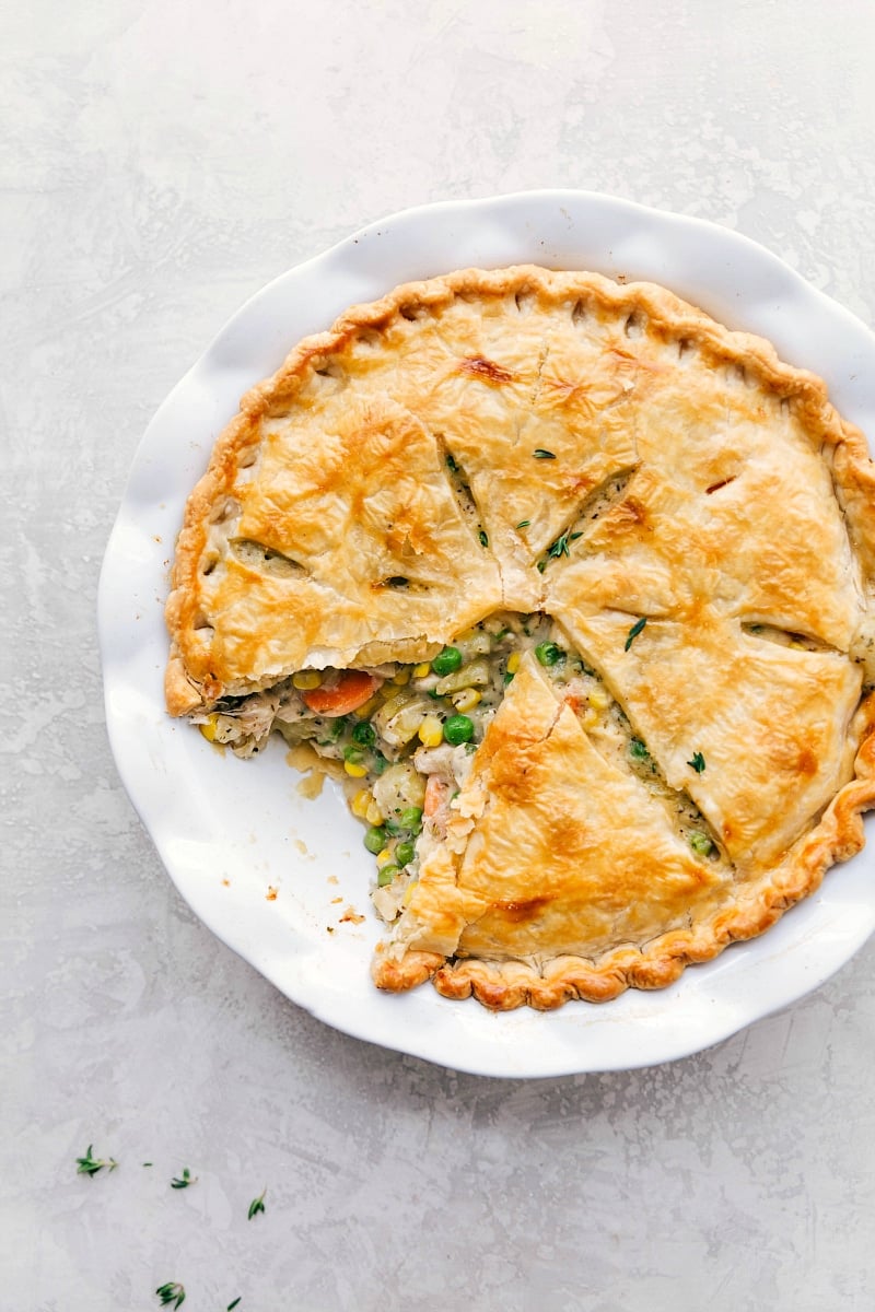 Freshly baked turkey pot pie with a golden, flaky crust, showing a serving already scooped out.