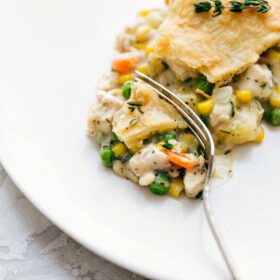 Savory and flavorful chicken pot pie on a plate, with a bite taken out to reveal its creamy center.
