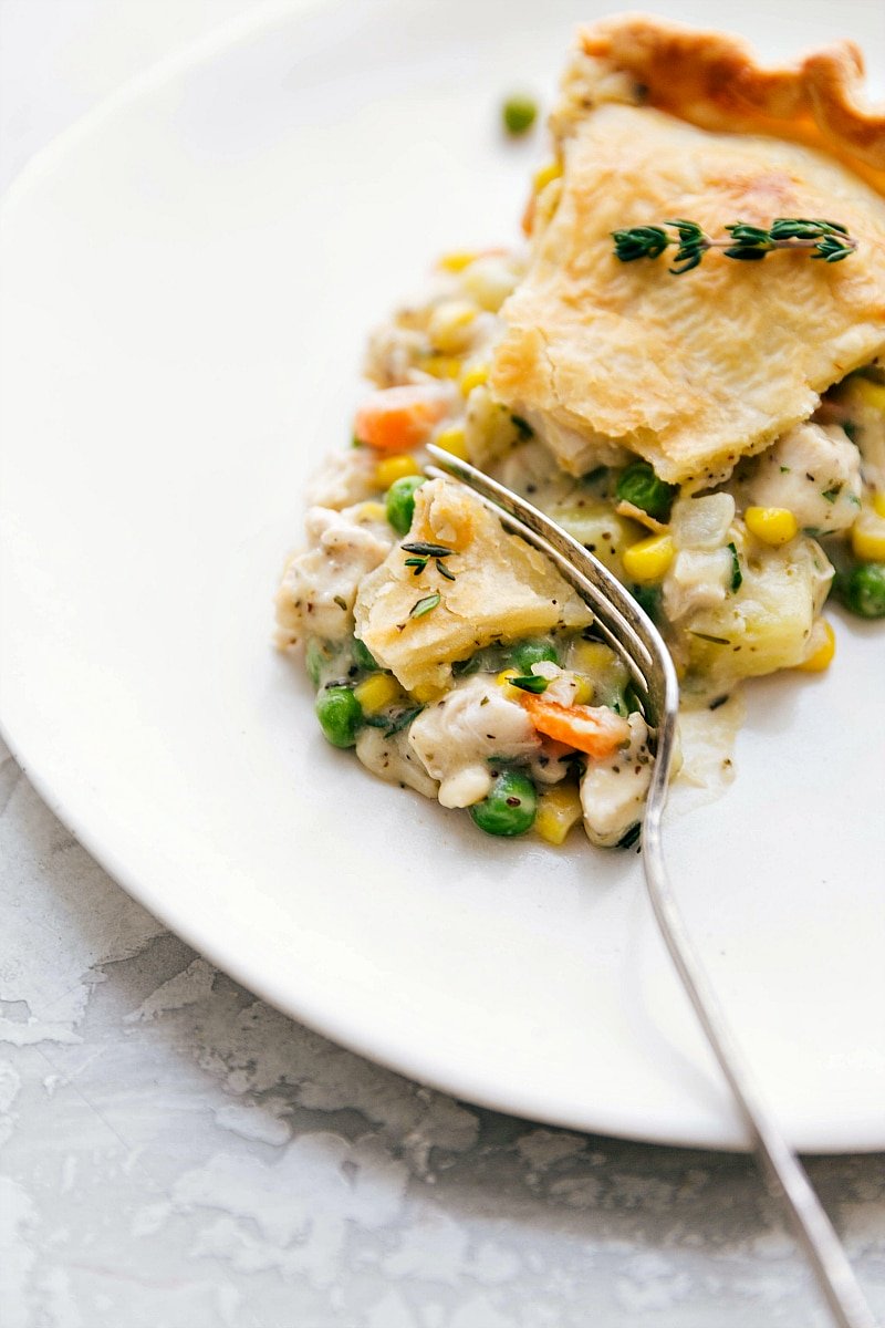 A slice of Chicken Pot Pie on a plate, with a bite being taken out of it.