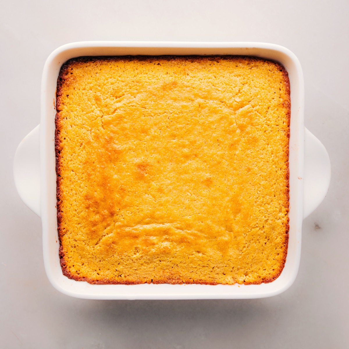 Freshly baked cornbread in a pan, golden-brown and ready to be enjoyed.