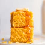 Stack of delicious and fluffy cornbread with honey and butter on a plate.