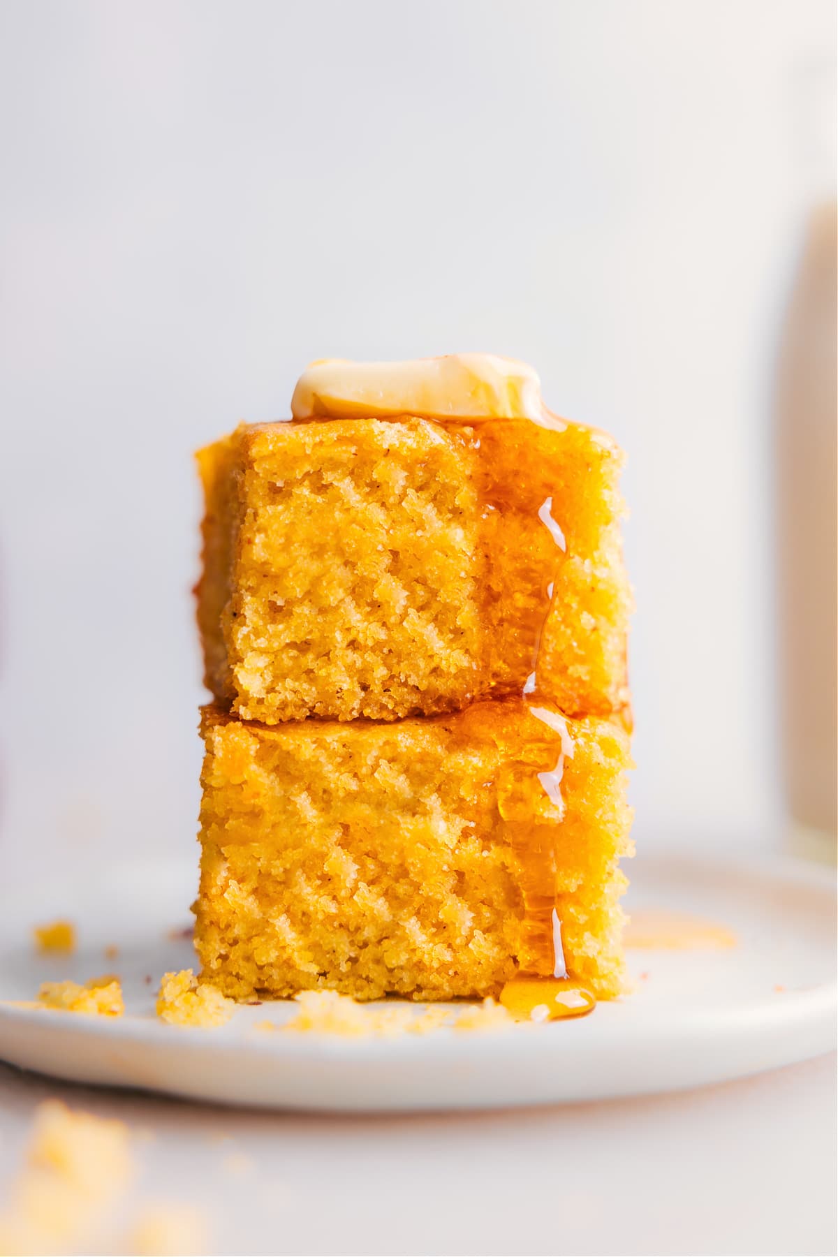 Stack of delicious and fluffy cornbread with honey and butter on a plate.
