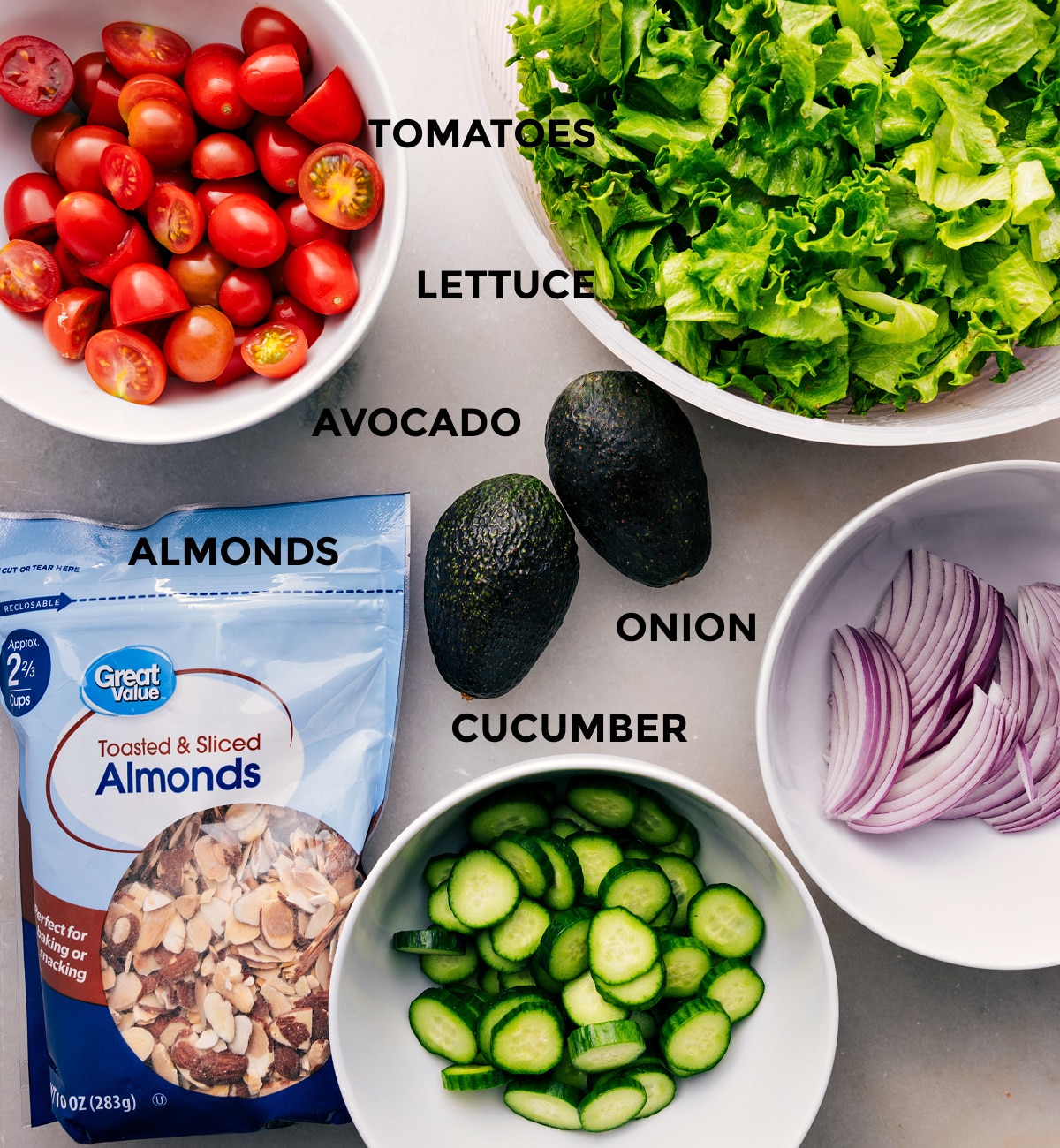 This recipe uses prepped ingredients for easy assembly: lettuce, tomatoes, avocado, onion, cucumber, and almonds.