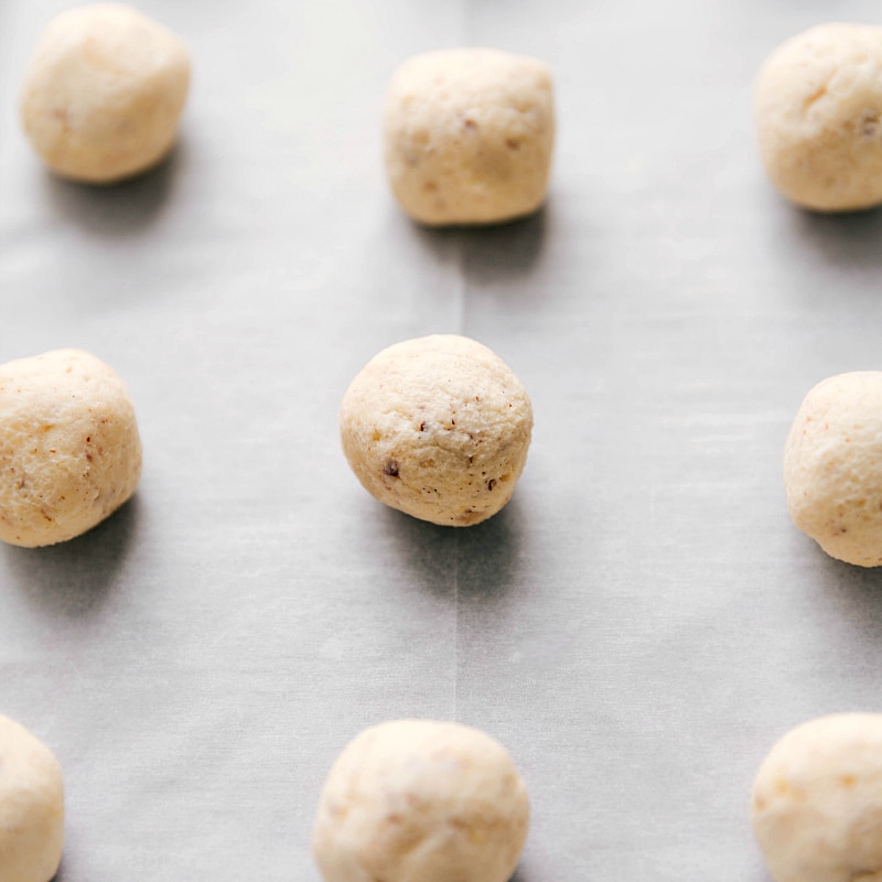 Rolled dough balls placed on a sheet pan, ready to be baked.