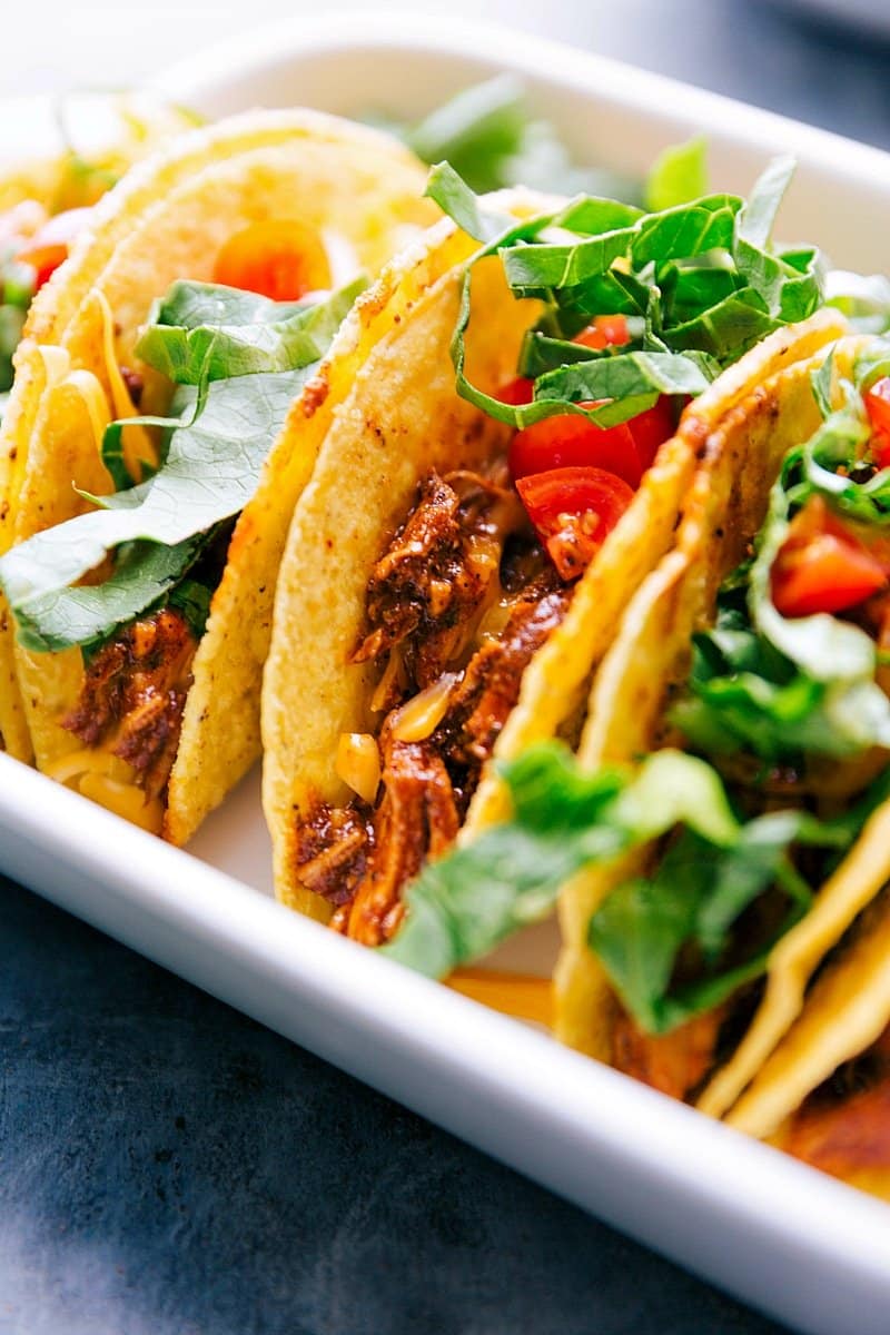 Up-close image of Rotisserie Chicken Tacos with toppings on, ready to be eaten.