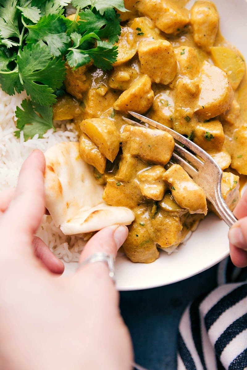 Yellow chicken curry served over rice and scooped onto naan bread.