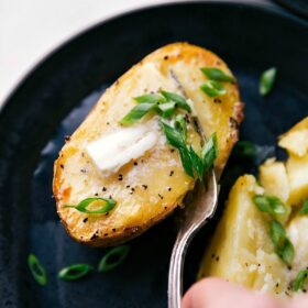 Freshly baked potatoes topped with melting butter and sprinkled with vibrant green chives, ready to be eaten.