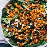 Thanksgiving salad filled with greens, butternut squash, feta, and more, ready to be tossed.
