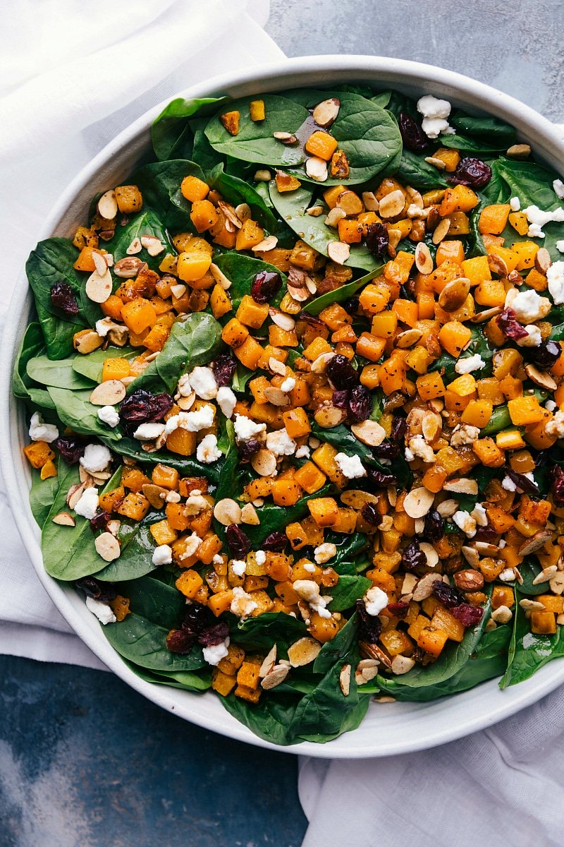 Thanksgiving salad filled with greens, butternut squash, feta, and more, ready to be tossed.