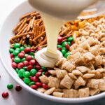 Melted white chocolate being poured over the mix of pretzels, chex, cheerios, and other ingredients.